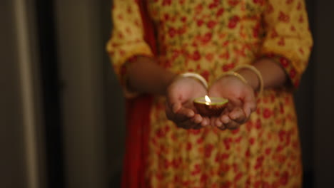 holding lit diya, indian woman in traditional sari celebrating festival of lights