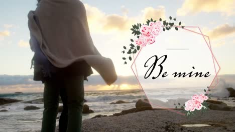 Couple-in-love-on-the-beach-with-Be-Mine-written-in-black-letters-