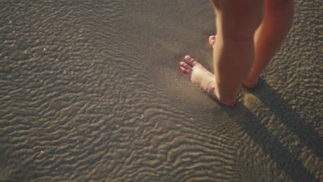 close up of woman feet standing on sandy beach sea water flowing gently vacation concept