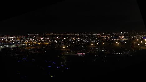 view from an airplane window during takeoff at night with city lights