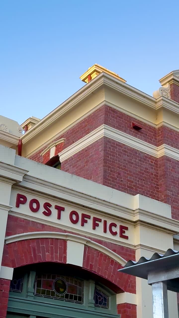 Inquadratura verticale di un edificio delle poste in stile vittoriano con mattoni rossi e dettagli architettonici.