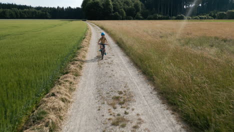 Drohnen-Luftaufnahme-Eines-Jungen,-Der-Durch-Die-Ruhige-Deutsche-Landschaft-Radelt