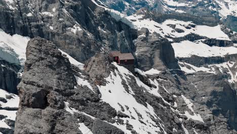 descending pan up shot of alpine hut with steep swiss cliffs in the background