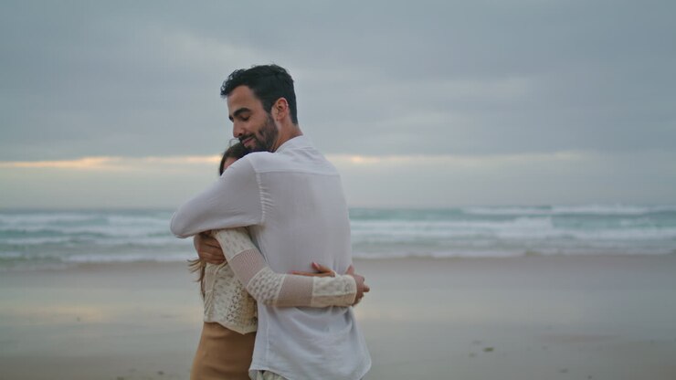 Carefree newlyweds cuddling evening beach closeup. Smiling man kissing woman