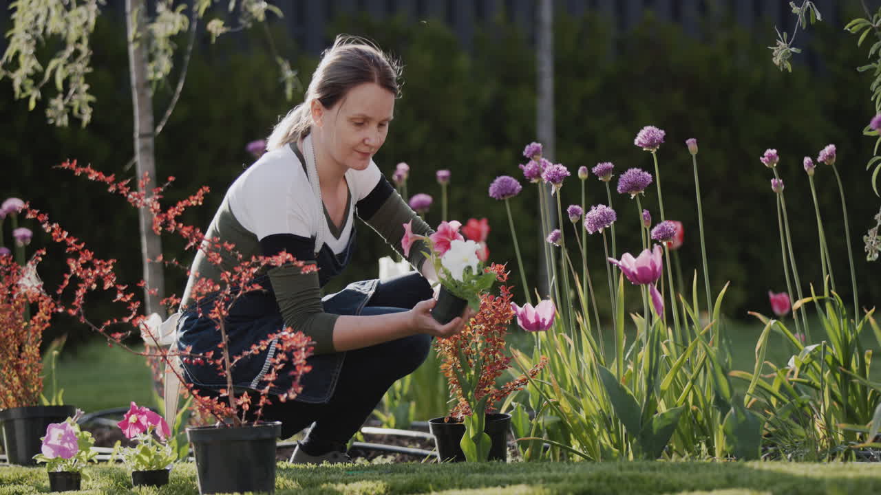 한 젊은 여성이 집 뒷마당에 꽃을 심고 있습니다.