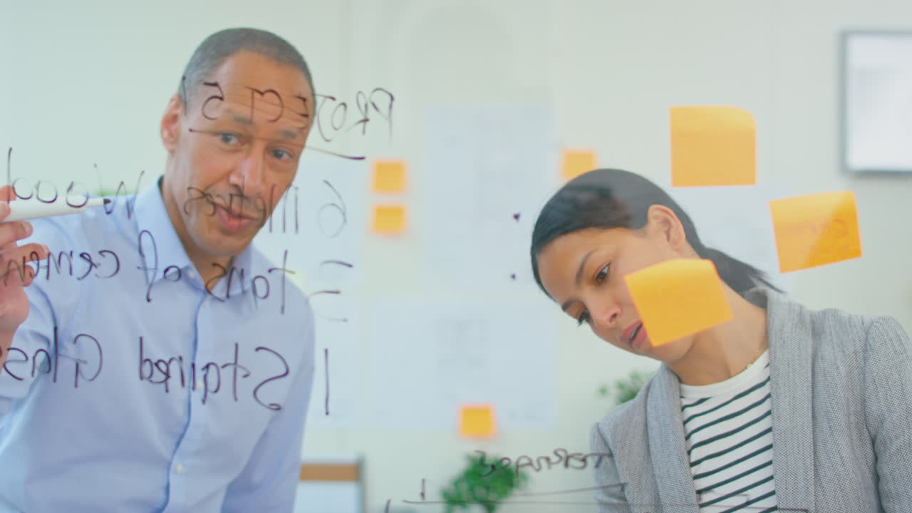 arquitectos masculinos y femeninos que trabajan en la oficina de planificación de un nuevo edificio en una pantalla transparente