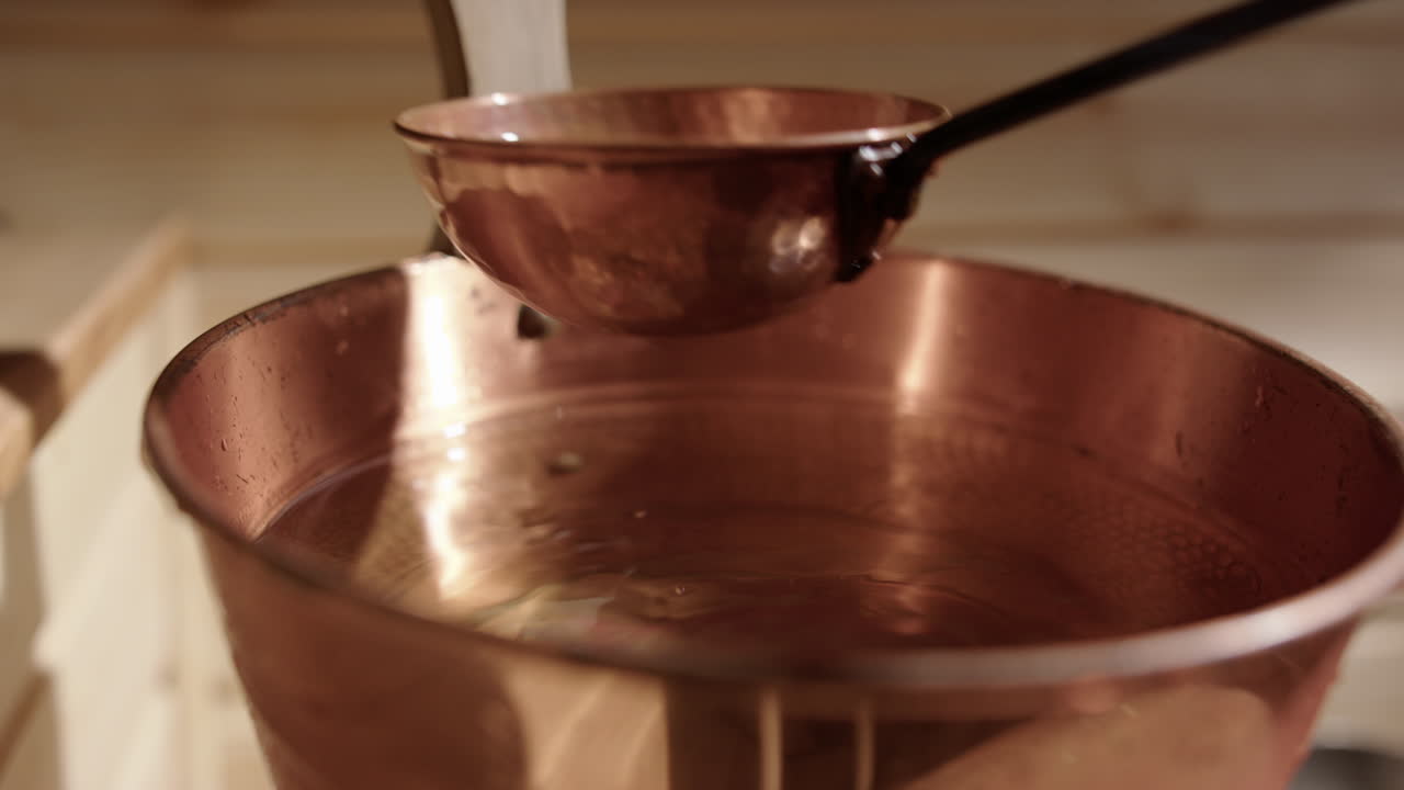 Scooping fresh water with copper ladle from copper sauna bucket, close-up
