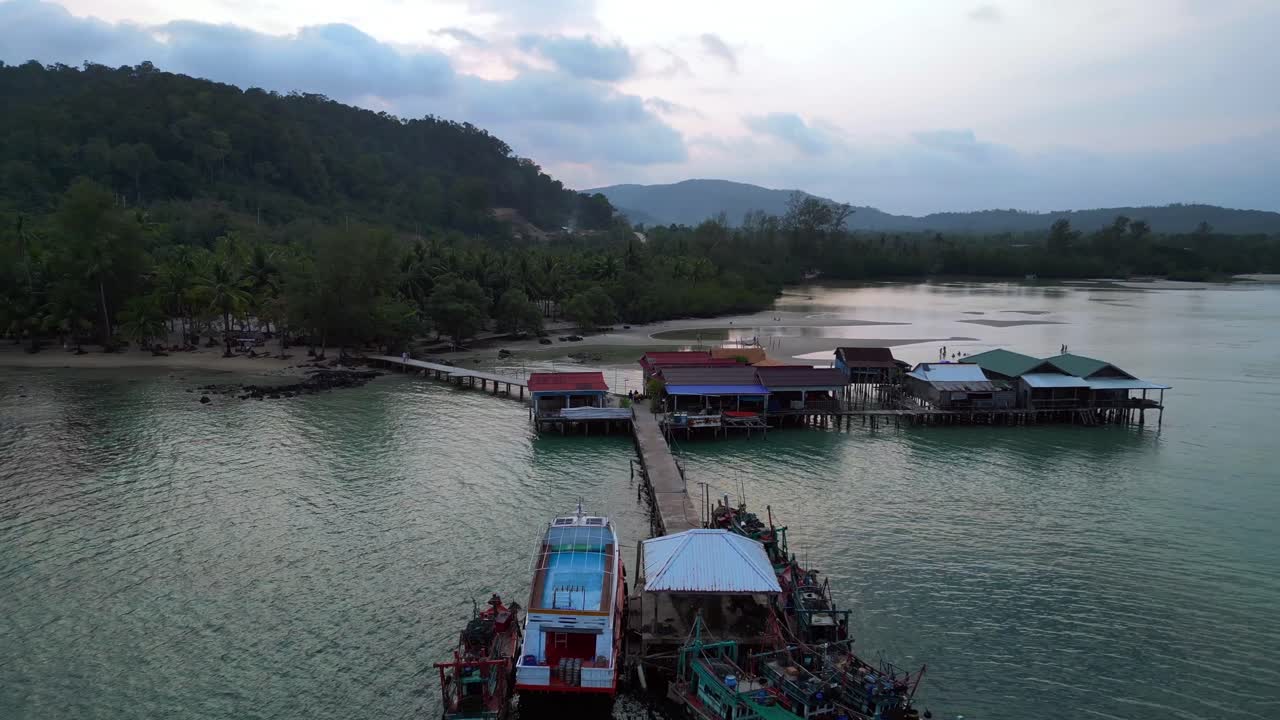 cambodia Koh Rong island, capturing the essence of tropical paradise with its lush palm trees, vibrant turquoise waters, and traditional stilt houses. Fabulous aerial view flight fly reverse drone
