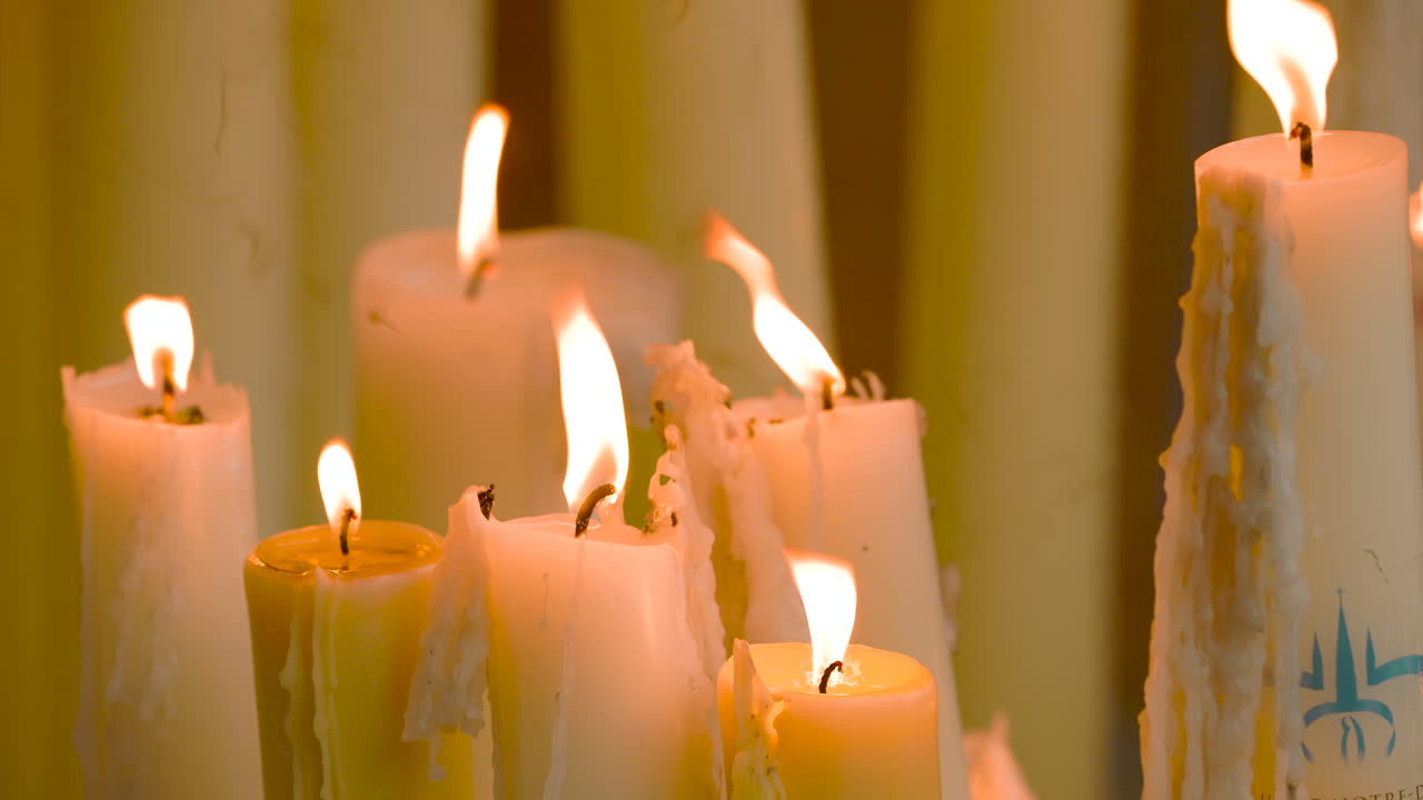 Votive candles burn and slowly consume. Faith and worship in the sanctuary of Lourdes.