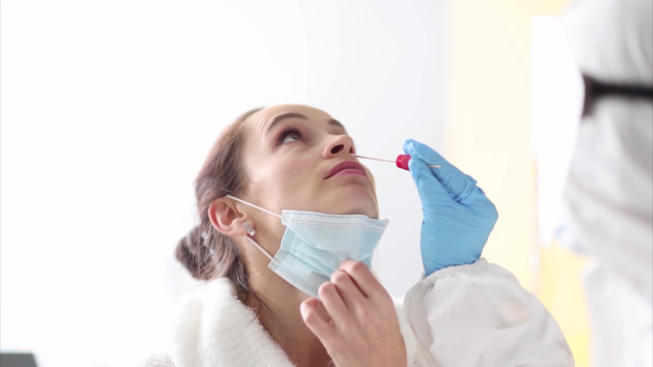 Donna con mascherina medica si sottopone a tampone nasale eseguito da un medico