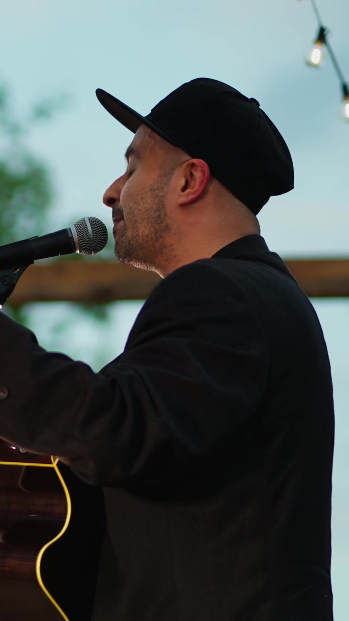 Uomo che canta e suona la chitarra acustica a un evento all'aperto