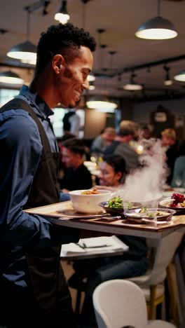 a lively restaurant scene, at eye level, featuring a smiling waiter serving steaming dishes video