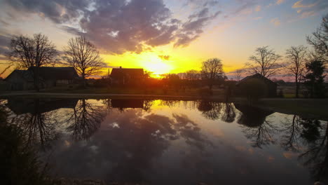 Blue-hour-to-sunrise-midday-timelapse-of-epic-sky-in-front-of-homes-reflecting-on-lake