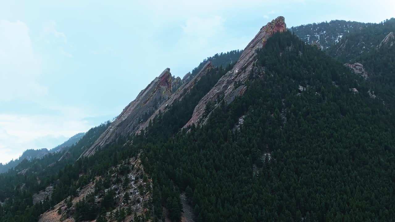 Drone view of Boulder Flatirons glowing under warm sunlight, surrounded by verdant vegetation