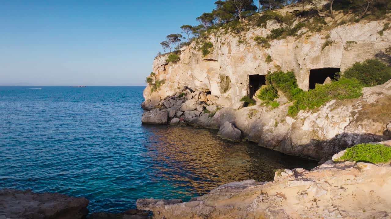 Flying near ancient limestone cliff caves, archaeological site in Mallorca