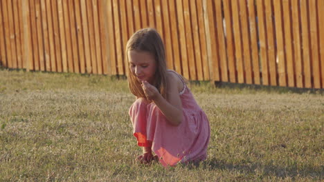 a young girl in a dress squatting on the grass