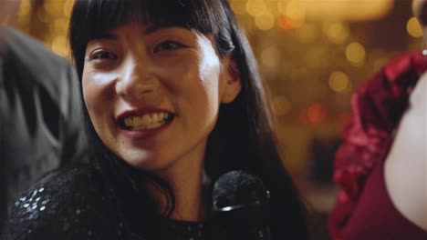 tracking shot of woman singing in karaoke bar with her friends