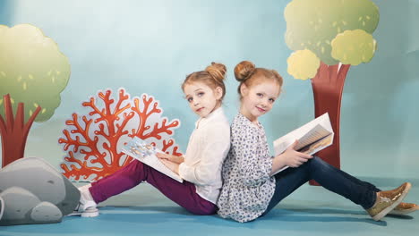 children with books in studio. little children girls reading sitting down