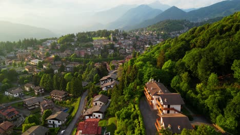 overhead view of selvino homes, winding roads and forests in soft morning light. mountains fade in background mist. shot at selvino, italy (selvino, italia)