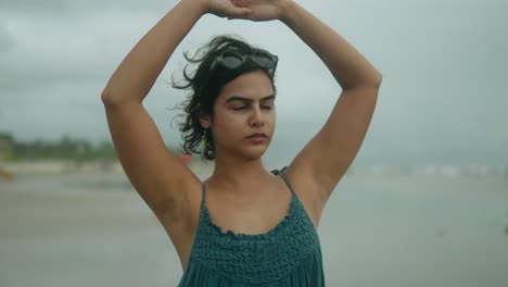 una atractiva joven asiática en un vestido púrpura estirándose con gracia después de hacer ejercicio en la playa, promoviendo un estilo de vida saludable y activo