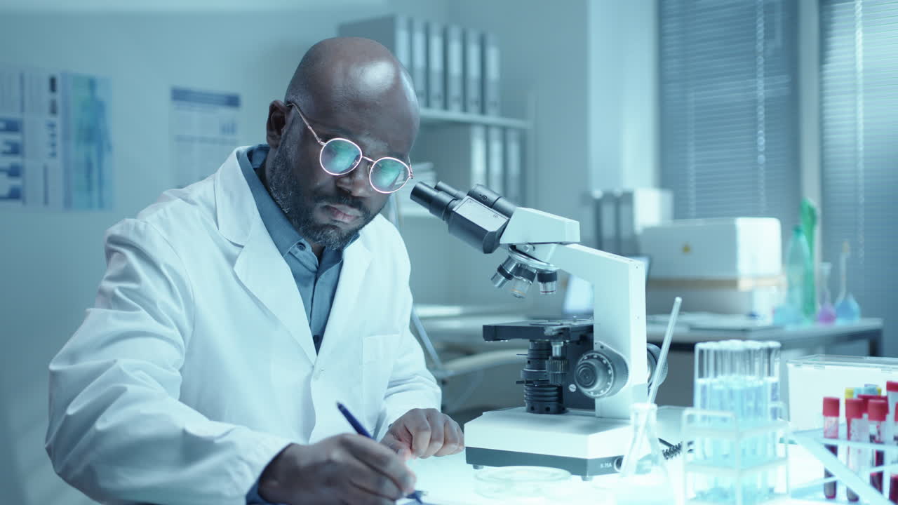 Scienziato afroamericano che esegue un'analisi di laboratorio con un microscopio
