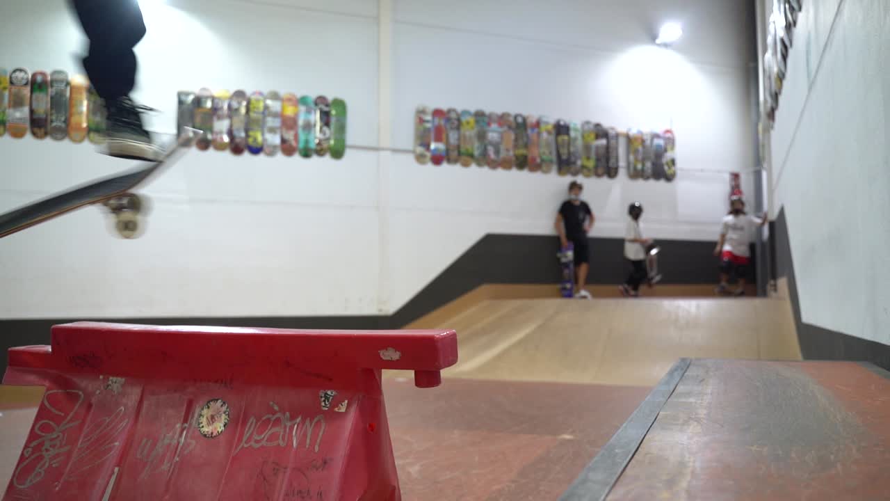 Slow motion shot of caucasian man jumping over obstacle with skateboard.Indoor skatepark during covid-19 time.