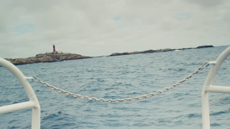 Blue-sea-and-a-lighthouse,-seen-from-the-front-deck-of-a-boat