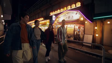 happy friends walking at night in a japanese city