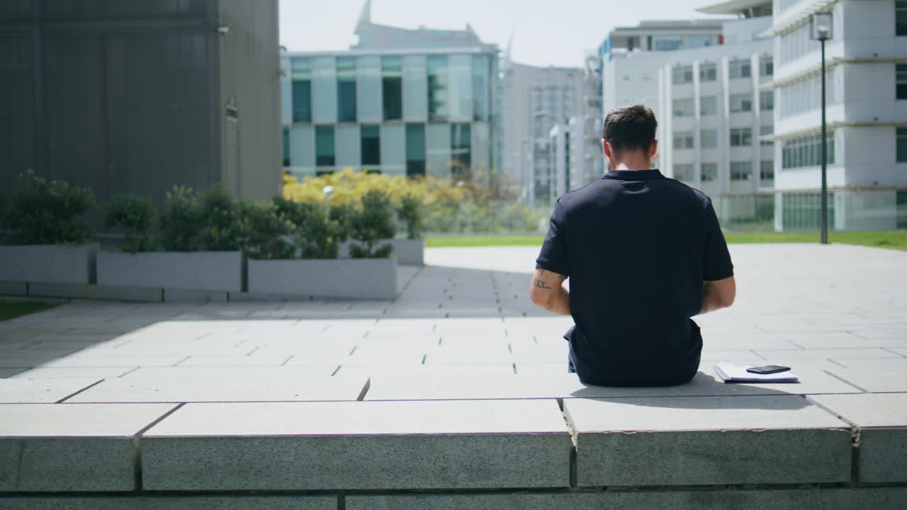 Business man typing laptop sitting urban bench. Freelancer working remotely