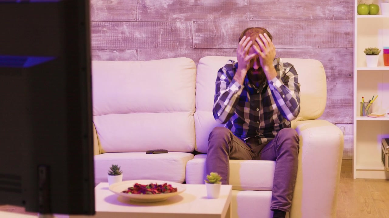 Uomo deluso che guarda sport in televisione a casa