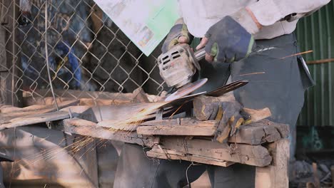 worker sharpening a broad blade with a grinding wheel