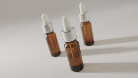 Close-up-of-three-glass-bottles-with-pumps-with-copy-space-on-white-background