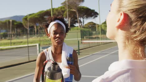 Video-Von-Glücklichen,-Vielfältigen-Tennisspielerinnen,-Die-Sich-Unterhalten-Und-Wasser-Trinken