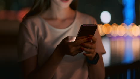 close-up de uma jovem com um smartphone em dubai à noite e escrevendo uma mensagem de texto