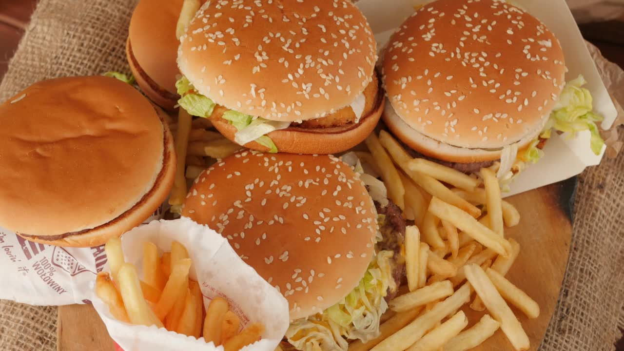 porción de comida no saludable, comida rápida, pila de hamburguesas, patatas fritas girando, vista desde arriba