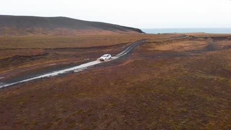 SUV-Conduciendo-A-Través-De-Un-Charco-De-Barro-En-Un-Camino-De-Grava-En-Un-Paisaje-Nórdico