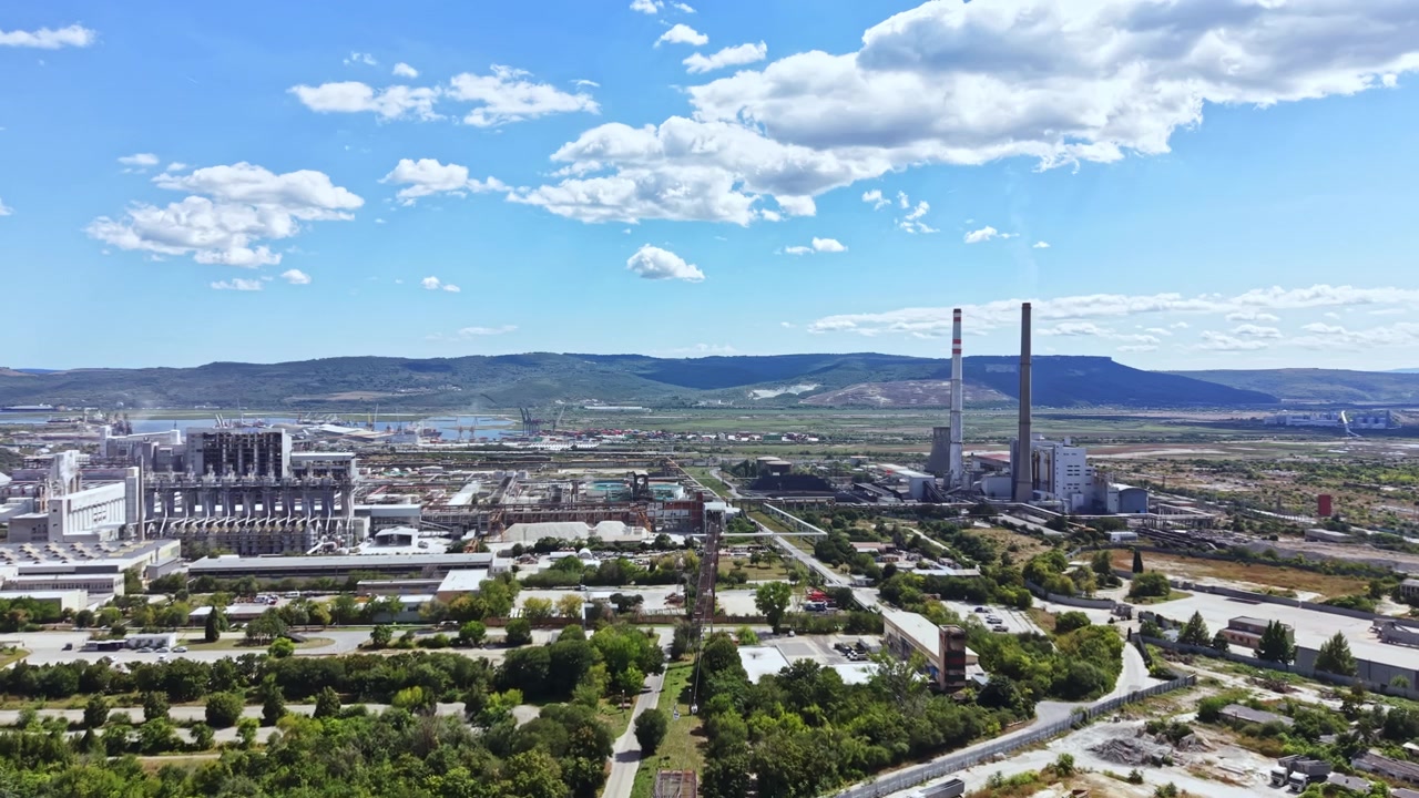 Vista de uma área industrial com chaminés e centrais elétricas sob um céu azul e nuvens em uma paisagem