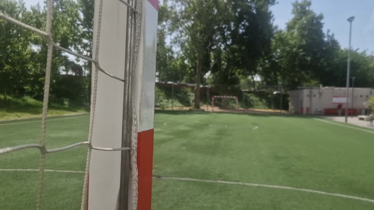 Camera panning from a close-up of the soccer goal net to reveal the empty green field