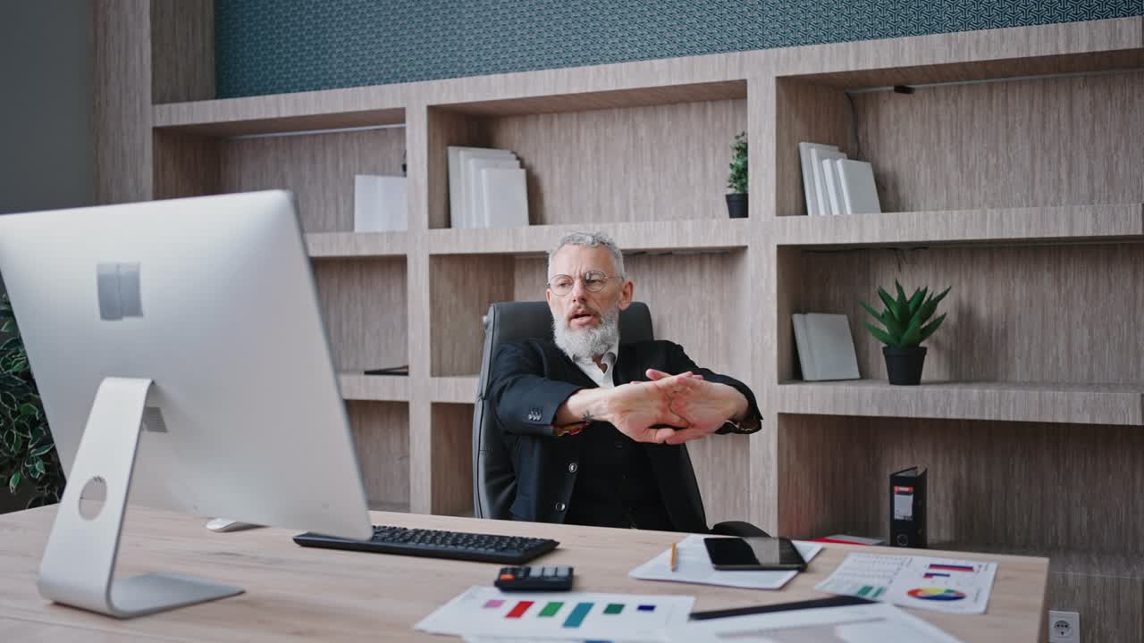 Uomo d'affari maturo e professionale con i capelli grigi seduto sul posto di lavoro e che inizia a lavorare al computer personale, zoom avanti