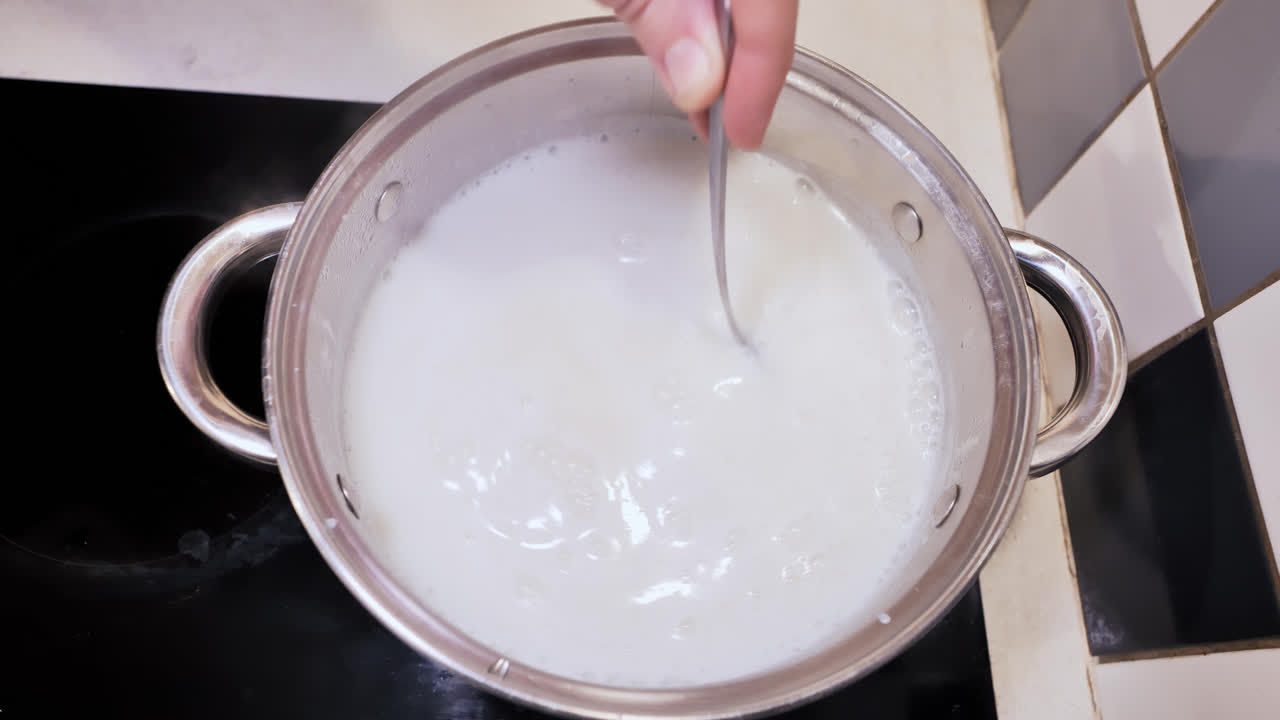 Top down view of man stirring semolina into boiling milk, classic tiled kitchen