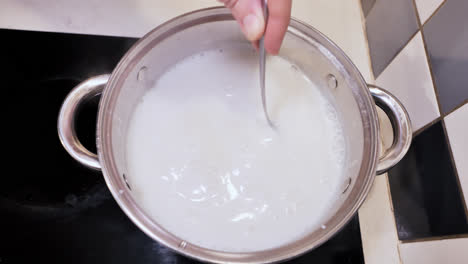 top down view of man stirring semolina into boiling milk, classic tiled kitchen