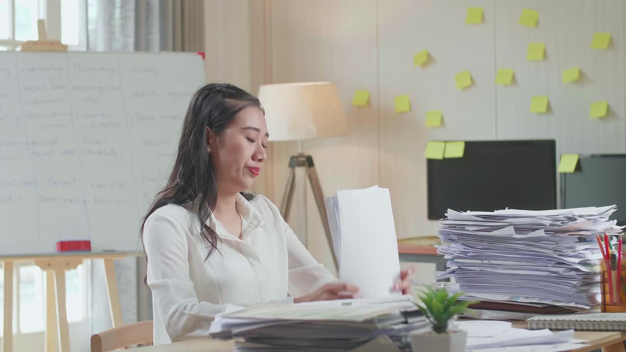 Tired Asian Woman Working Hard With Documents At The Office