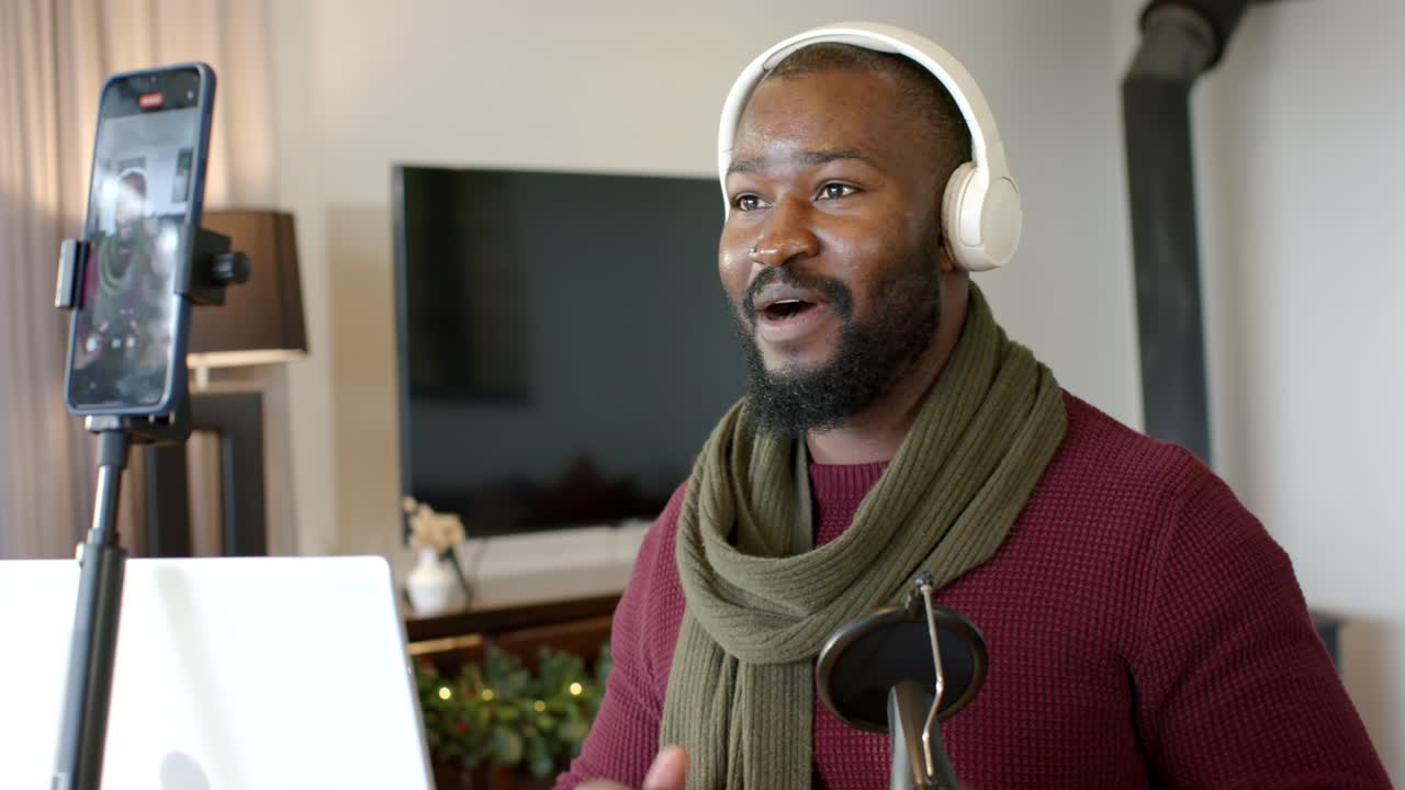 African American man greeting viewers via laptop wearing headset and sharing ideas in home office