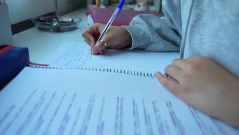 chica dedicada estudiando y tomando notas a mano en la mesa