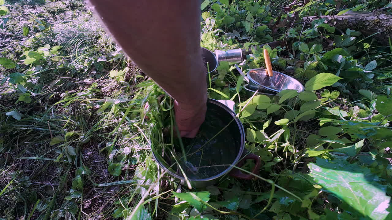 mientras acampa, fregando las ollas y sartenes limpios con hierba