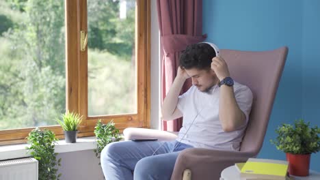 Hombre-Mirando-Por-La-Ventana-Y-Escuchando-Música-Con-Auriculares.