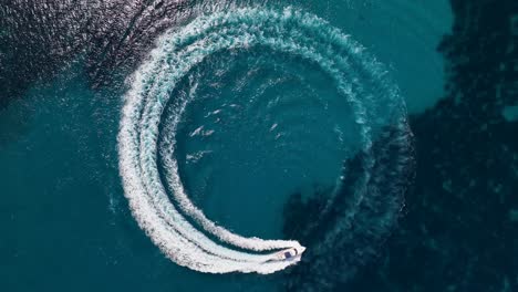 Top-down-drone-shot-of-boat-driving-in-a-circle