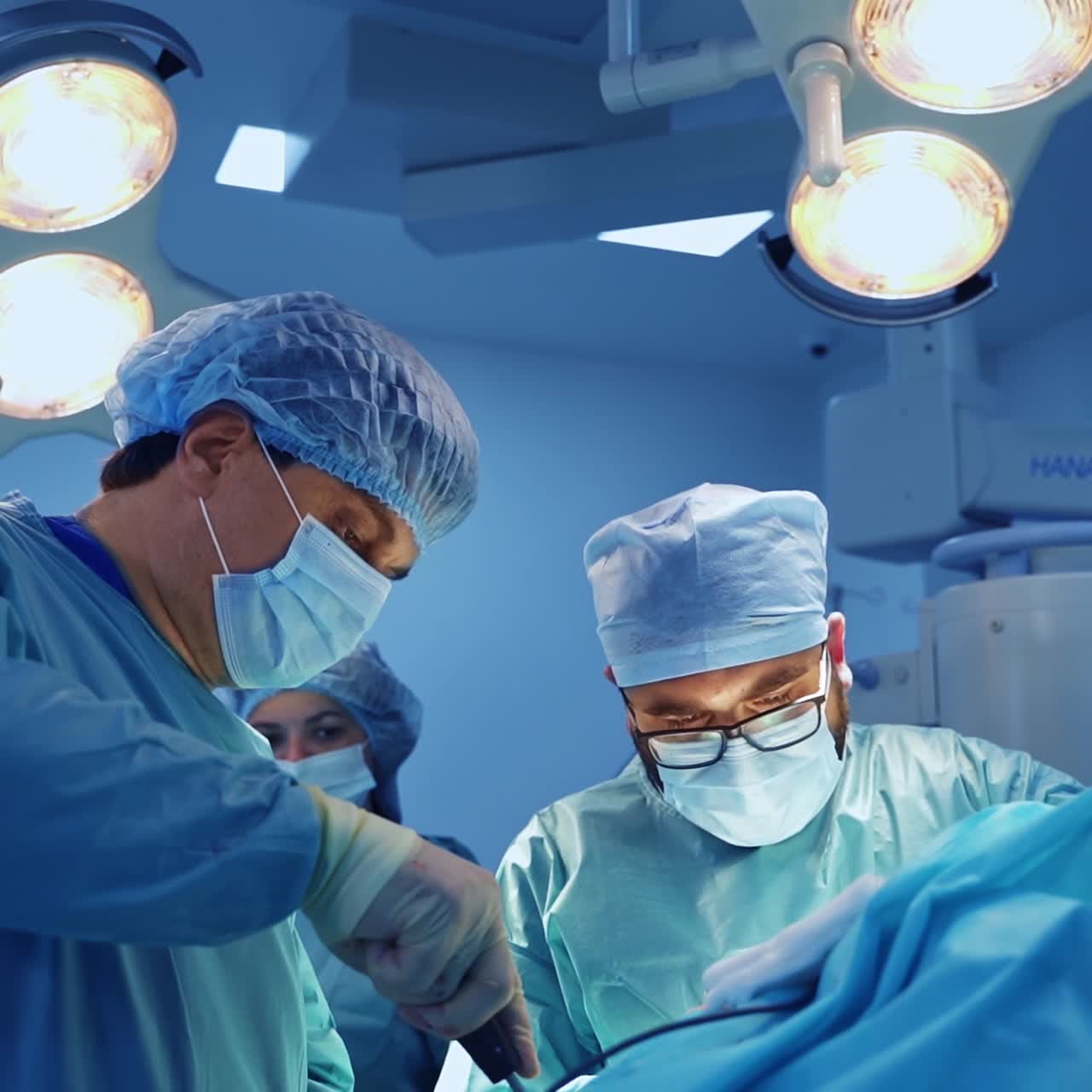 Trauma treating operation in the modern operational room. Surgeons use metal tools at surgery. Nurse at backdrop