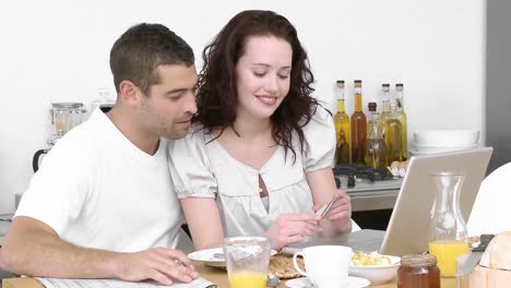 pareja trabajando con una computadora portátil en la cocina