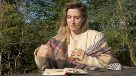 mujer ucraniana marcando página de cuaderno estudiando al aire libre